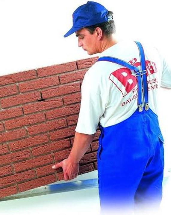 Monteur bringt ein Böger-Systemklinker-Element mit Klinker und Dämmung direkt an die Wand an